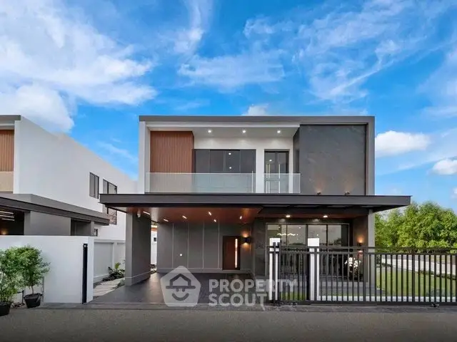 Modern two-story house with sleek design and spacious driveway under a clear blue sky.