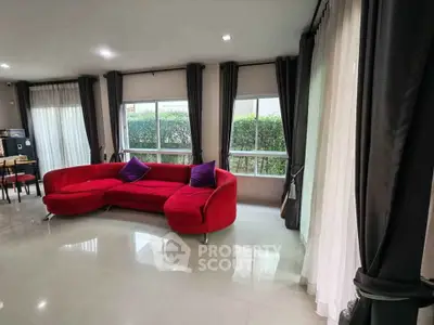 Spacious living room with red sofa and large windows offering garden views