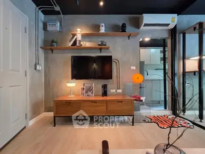 Modern living room with stylish decor and open kitchen layout, featuring a sleek TV setup and contemporary lighting.
