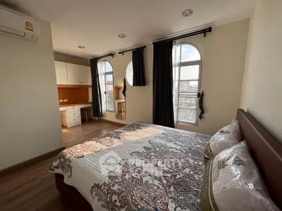 Spacious bedroom with elegant decor and large windows offering city views