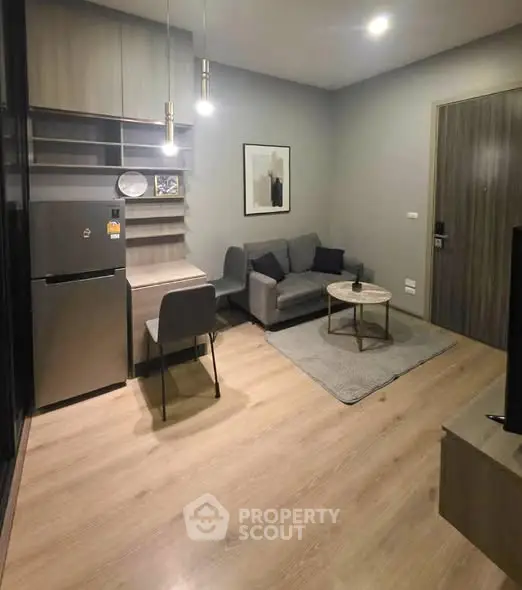 Modern living room with cozy sofa, stylish decor, and sleek kitchen area.