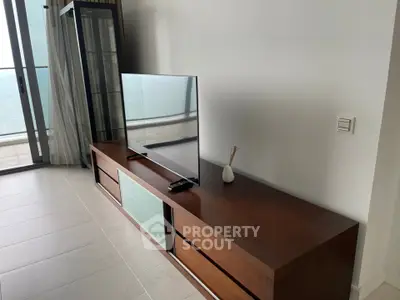 Modern living room with sleek TV stand and ocean view balcony, perfect for relaxation and entertainment.