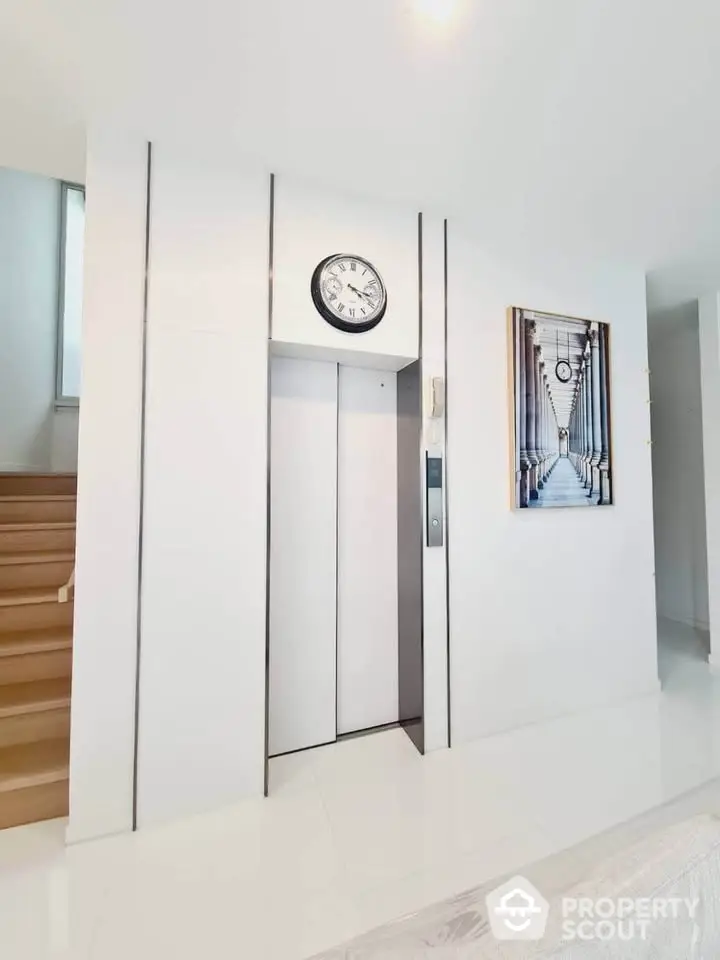 Modern home elevator with sleek white design and decorative wall clock