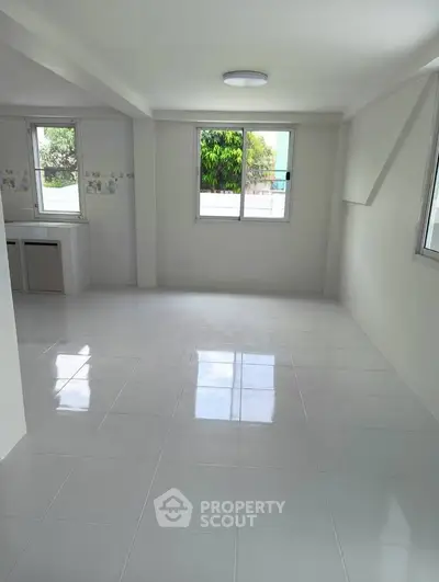 Spacious and bright living room with large windows and tiled flooring, perfect for modern living.
