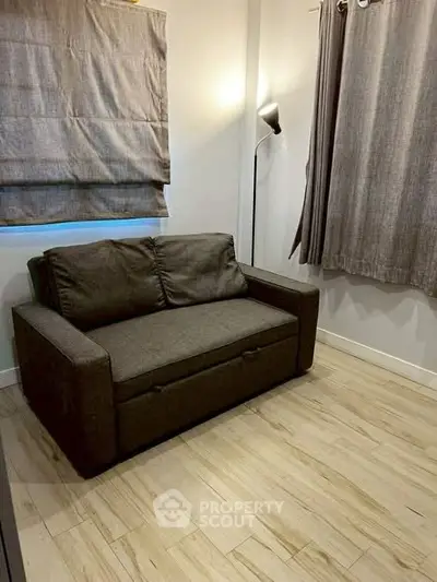 Cozy small living room with a dark sofa and modern lighting