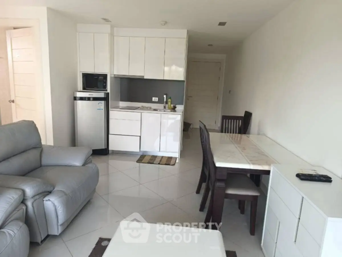 Modern open-plan living room with sleek kitchen and dining area, featuring contemporary furniture and appliances.