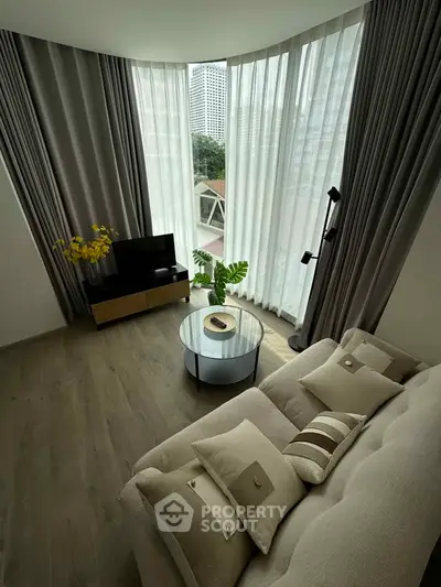 Stylish living room with floor-to-ceiling windows and modern decor in urban apartment.