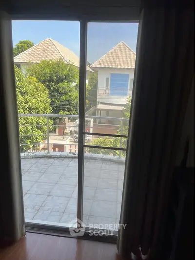 Charming balcony view with lush greenery and neighboring houses, perfect for relaxation.