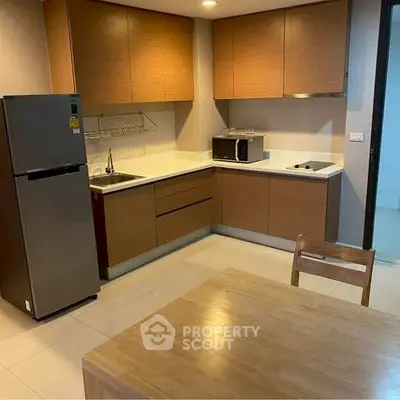 Modern kitchen with wooden cabinets and dining table in cozy apartment.