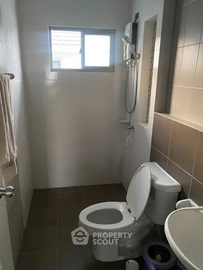 Compact bathroom with modern fixtures and natural light from window.