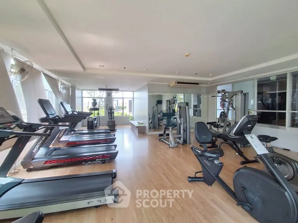 Spacious modern gym with state-of-the-art fitness equipment and large windows for natural light.