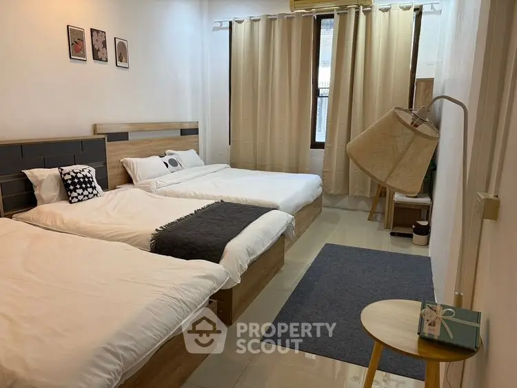Spacious bedroom with two cozy beds and modern decor in a well-lit apartment.