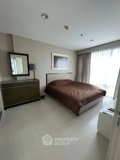 Spacious bedroom with modern decor and large window for natural light.