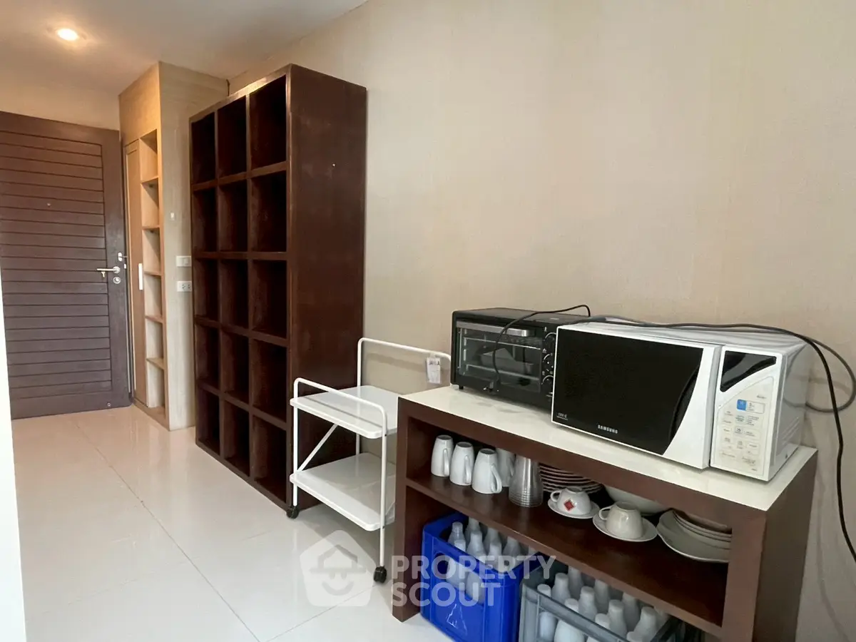 Modern kitchen with microwave and storage shelves in a sleek apartment