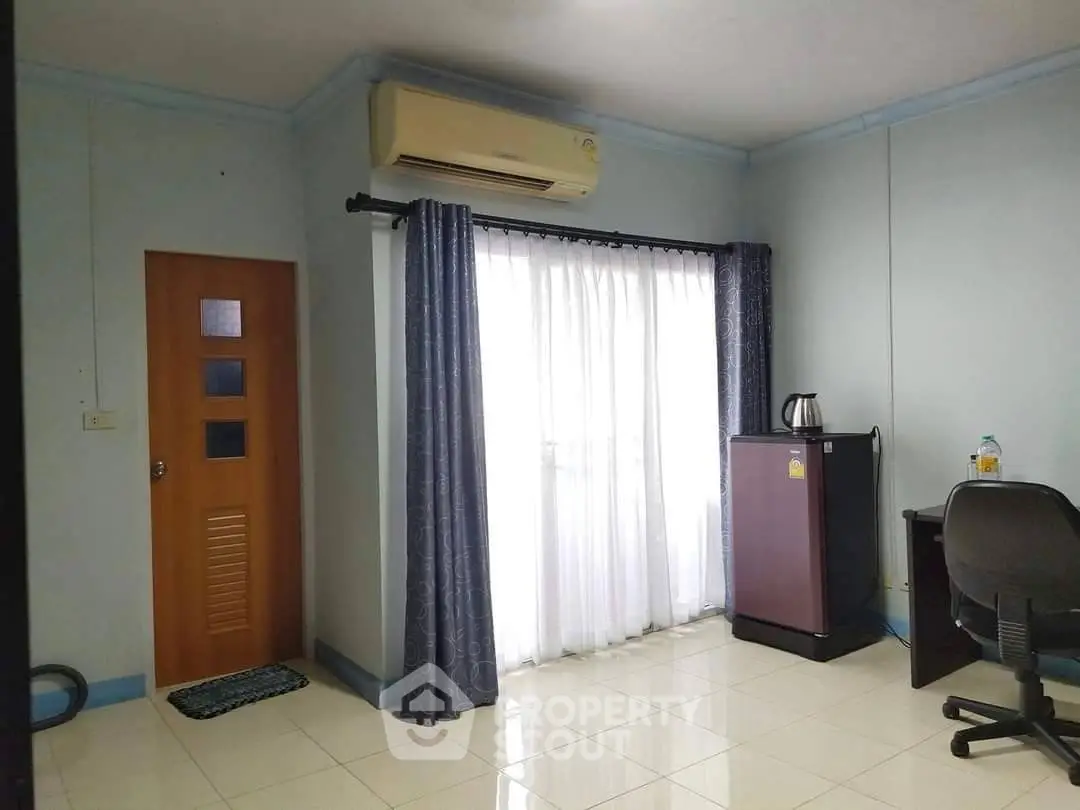 Cozy room with air conditioning, desk, and mini fridge, ideal for comfortable living.