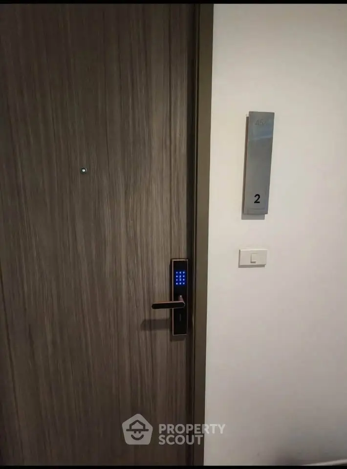Modern apartment door with digital lock and room number, showcasing secure entryway.