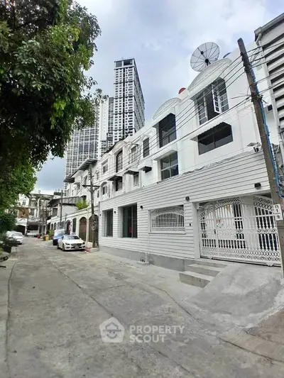 Charming urban street view with modern townhouses and high-rise buildings in the background.