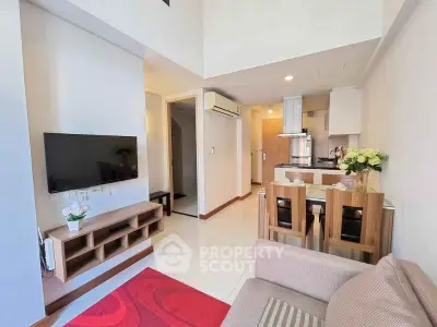 Modern living room with open kitchen, featuring sleek furniture and bright lighting.