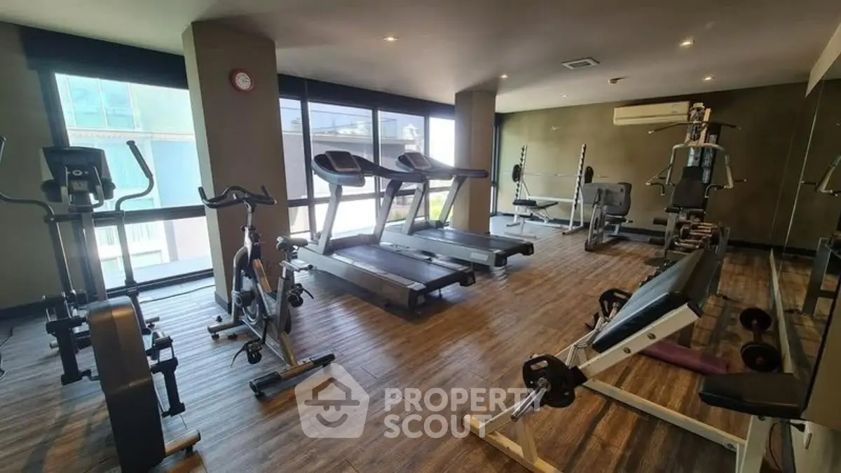 Modern gym with state-of-the-art equipment and large windows in a luxury apartment building.