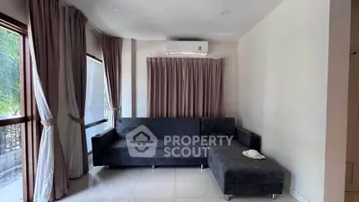 Modern living room with sleek gray sectional sofa and large windows with elegant curtains.