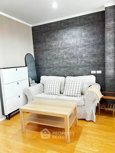 Cozy living room with modern decor, featuring a comfortable sofa, stylish brick accent wall, and wooden flooring.