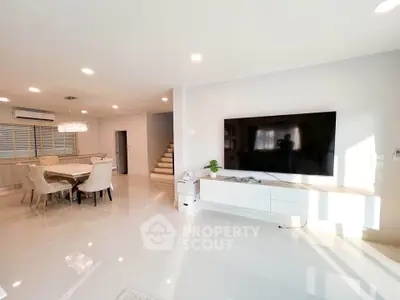 Spacious modern living room with large TV and dining area, perfect for family gatherings.