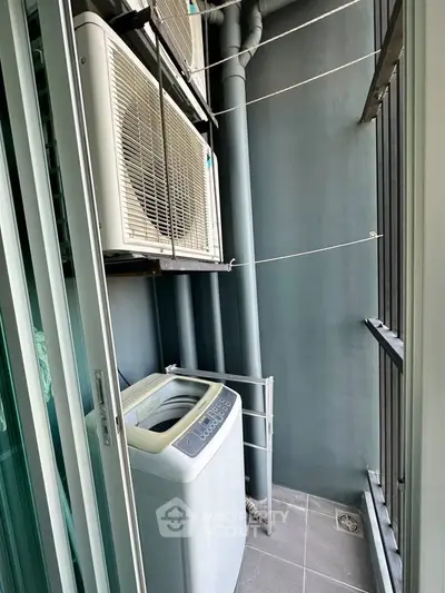Compact balcony with washing machine and air conditioning unit in modern apartment.
