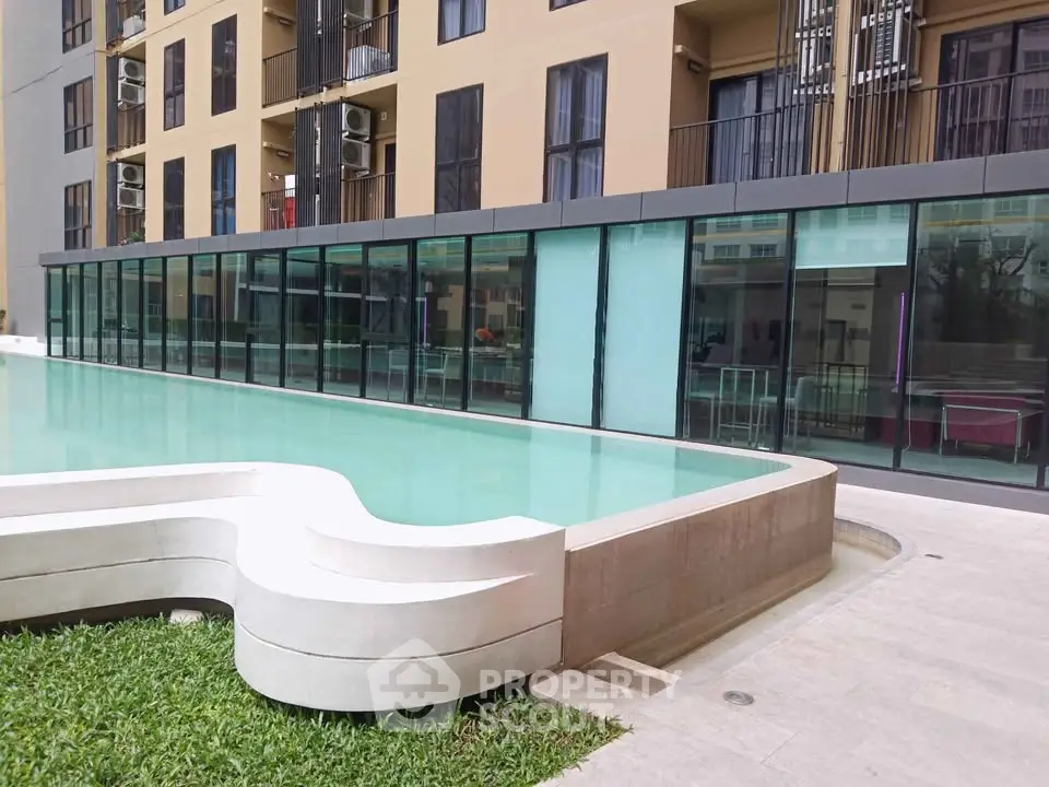 Modern apartment building with sleek poolside view and glass facade.