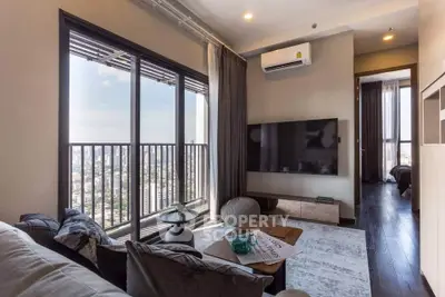 Modern living room with city view, large TV, and stylish decor in high-rise apartment.
