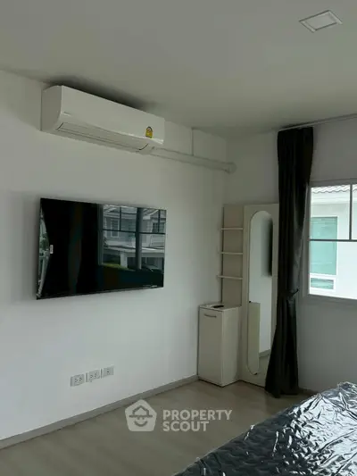 Modern bedroom with wall-mounted TV and air conditioning in a stylish apartment.