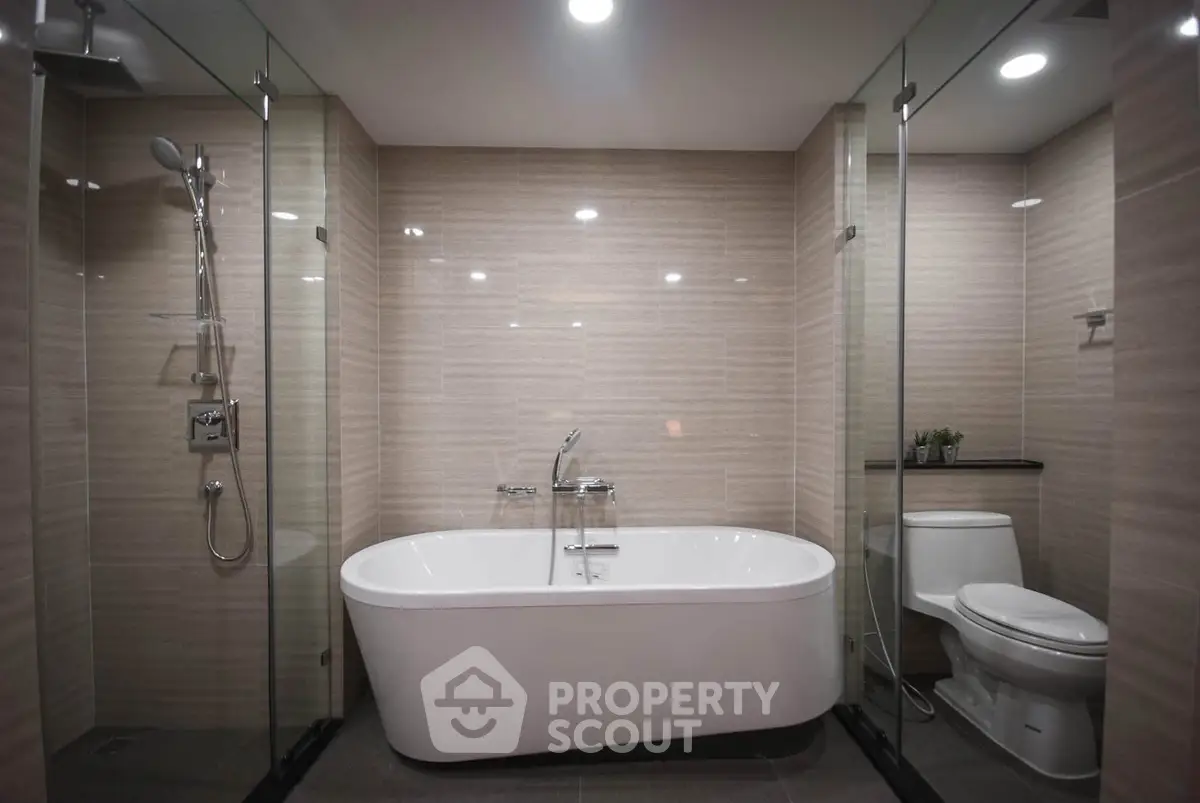 Luxurious modern bathroom with freestanding bathtub and glass shower enclosure.