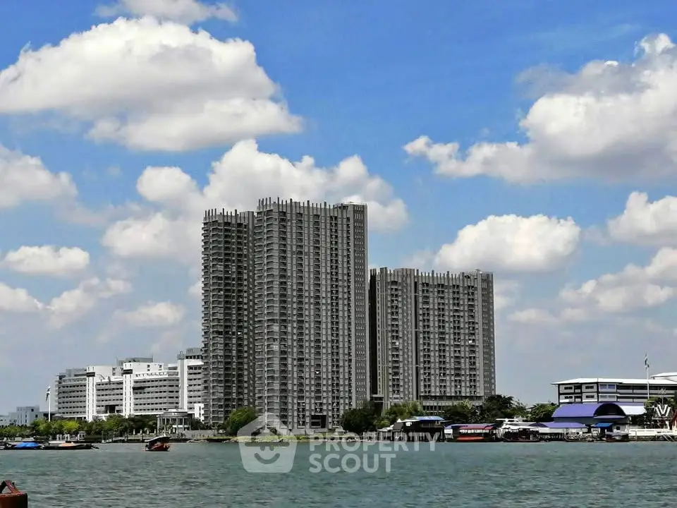 Stunning riverside high-rise buildings with modern architecture under a bright blue sky.