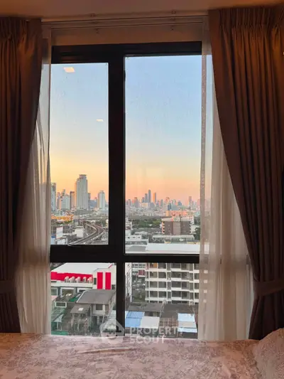 Stunning cityscape view from a cozy bedroom window at sunset, perfect for urban living enthusiasts.