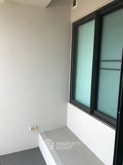 Modern balcony with sleek design and large window, perfect for relaxation.