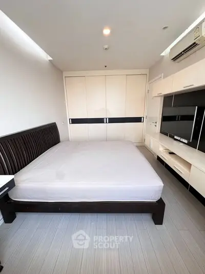 Spacious bedroom with modern furnishings and ample storage in a stylish apartment.