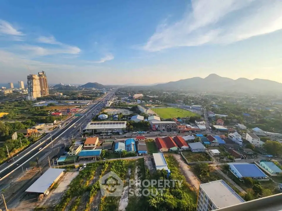 Stunning aerial view of a vibrant cityscape with mountains in the background, showcasing urban and natural beauty.