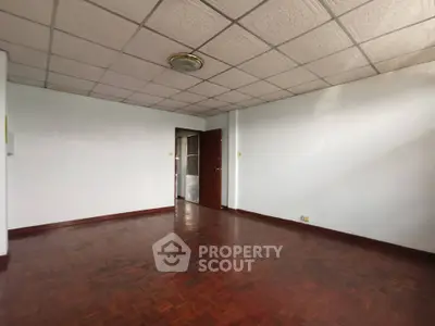 Spacious empty room with polished red wooden flooring and white walls, perfect for custom interior design.