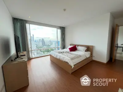 Spacious bedroom with city view and modern furnishings in high-rise apartment