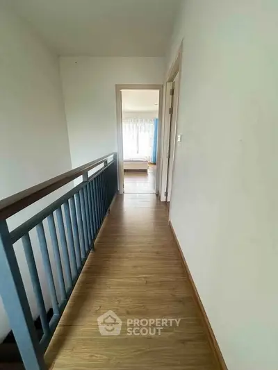 Bright hallway leading to a cozy bedroom with wooden flooring and natural light.
