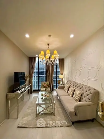 Elegant living room with plush sofa, chic chandelier, and large window view in modern apartment.