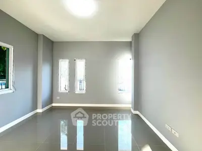 Spacious empty room with glossy tiled floor and large windows, perfect for customization.