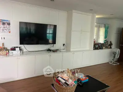 Spacious living room with built-in cabinets and large TV, perfect for family gatherings.
