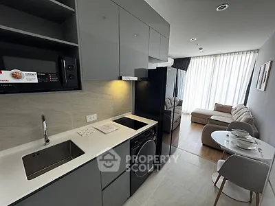 Modern open-layout kitchen with sleek appliances and cozy living area in a stylish apartment.
