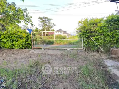 Spacious vacant land with gated entrance and lush greenery, ideal for development opportunities.