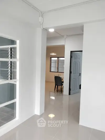 Modern interior with sleek flooring and minimalist design, featuring a dining area and large windows.