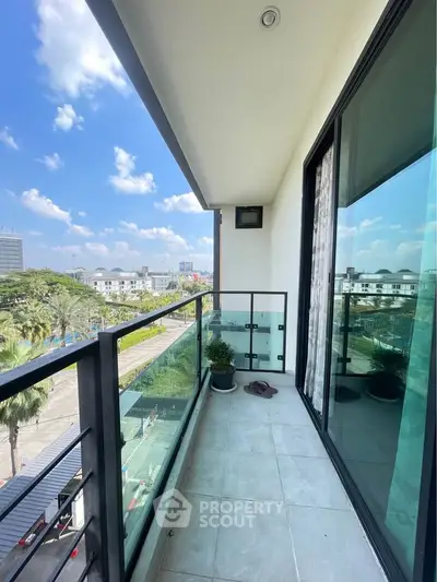 Spacious balcony with glass railing offering a stunning city view under a clear blue sky.