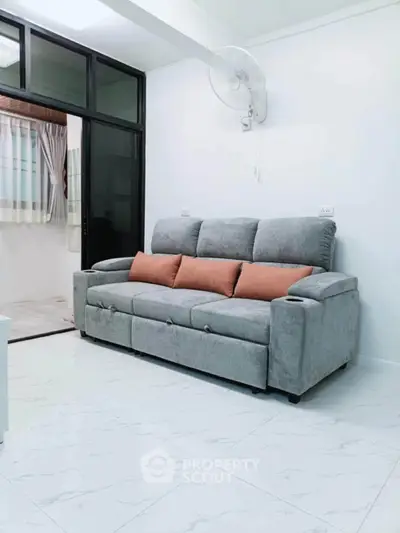 Modern living room with stylish gray sofa and wall-mounted fan