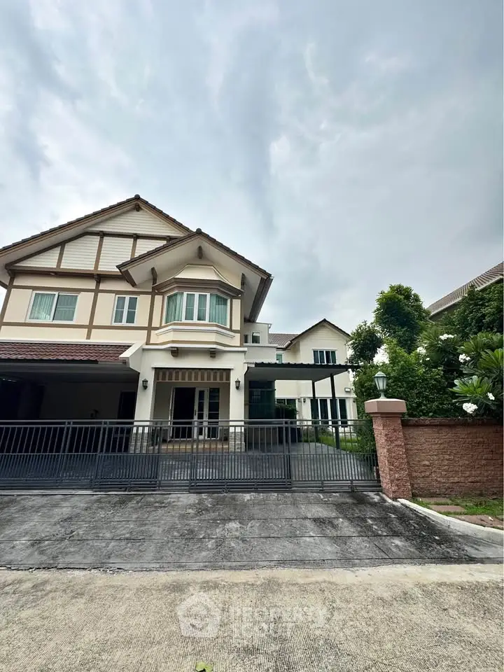 Charming two-story house with gated driveway and lush greenery, perfect for family living.