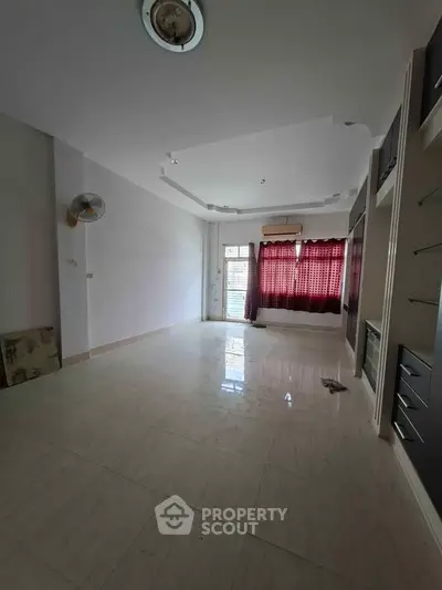 Spacious unfurnished living room with tiled flooring and large window for natural light.