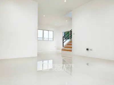 Spacious modern living room with glossy white floors and staircase